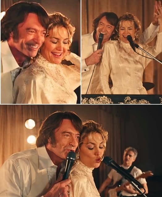 “YOU CAN FEEL IT, RIGHT?” Hugh Jackman Laughed Into The Mic — And The Room Absolutely Did. From The Moment He And Kate Hudson Launched Into “Sweet Caroline” From Song Sung Blue (2025), The Energy Changed Instantly. Kate Beamed Mid-verse, Teasing, “How Can You Not Sing Along To This One?” As The Crowd Answered Her Before The Band Even Could. Their Voices Blended With Effortless Warmth, Turning A Familiar Anthem Into Something Freshly Alive. Every Chorus Hit Louder Than The Last, Phones Rose Into The Air, And Strangers Sang Like Old Friends. One Fan Could Be Heard Shouting, “This Is Pure Joy!” While Another Later Wrote, “I Didn’t Come For A Singalong — I Came For A Memory, And They Gave Us One.”